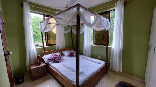a bedroom with a canopy bed in a room with windows at The Costal Sunny Daze,076 8976 732 in Mombasa