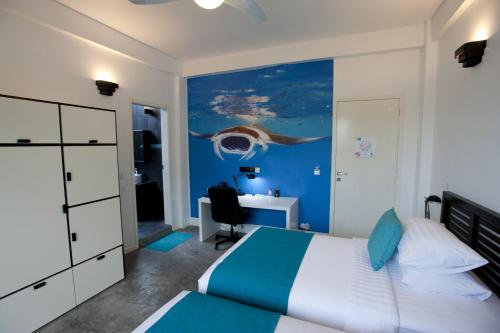 a bedroom with a bed and a desk with a computer at Boutique Beach All Inclusive Diving Hotel in Dhigurah