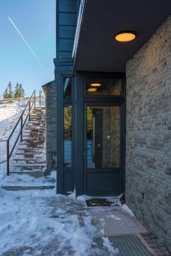 a black door on a brick building with snow at Casa Valley Paradiso - Jahorina in Jahorina
