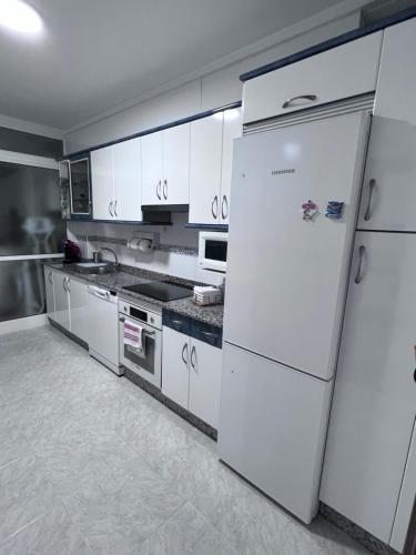 uma cozinha com armários brancos e um frigorífico em Mi pisito en el Temple em La Coruña
