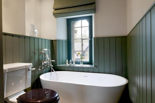 a bathroom with green walls and a tub and a toilet at The Penn in Windermere