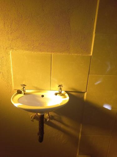 d'un lavabo dans une salle de bains avec un mur jaune. dans l'établissement Tanganani guest house, à Doornrandjies