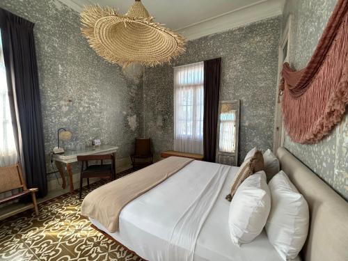 a bedroom with a large bed and a chandelier at Historic House Hotel boutique in Mérida