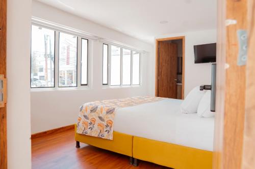 a bedroom with a bed and a tv and windows at Hotel Encanto in Manizales