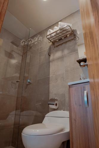 a bathroom with a toilet and a glass shower at Hotel Encanto in Manizales