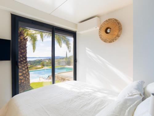 une chambre avec un lit blanc et une grande fenêtre dans l'établissement Cocotiers, aux Issambres