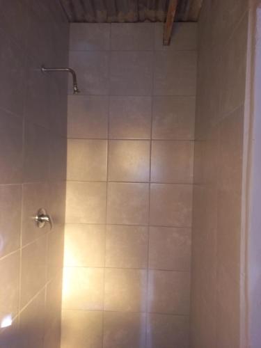 La salle de bains est pourvue d'une douche et de carrelage blanc. dans l'établissement Tanganani guest house, à Doornrandjies