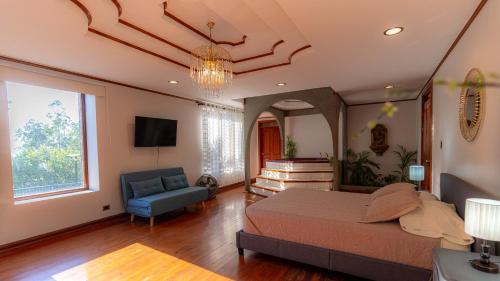 ein Schlafzimmer mit einem Bett, einem Sofa und einem TV in der Unterkunft Casa Familiar la Tortuga in Heredia