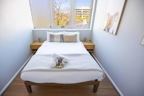 a small bedroom with two beds and two windows at Central Getaway, On Rundle St in Adelaide