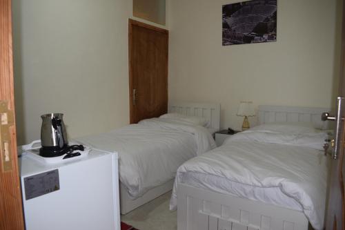 2 camas en una habitación de hotel con sábanas blancas en Petra rose city en Wadi Musa