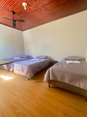 two beds in a room with a wooden ceiling at Sossego e Fé in Ouro Fino