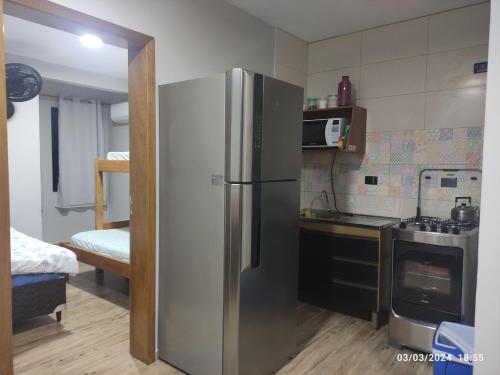 uma cozinha com um frigorífico de aço inoxidável num quarto em kitnets Porto Marujo em Paranaguá