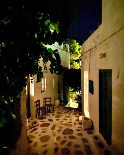an alley with chairs and a door in a building at School House with Panoramic View in Serifos Chora