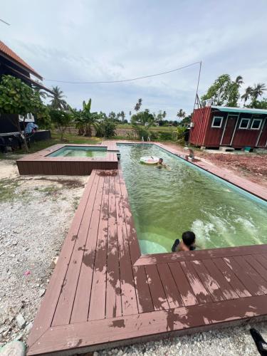 um homem a nadar numa piscina com um deque de madeira em HOMESTAY Kampong KOTA AUR Resort with swimming pool, Kepala Batas, SEBERANG PERAI, PENANG -MOTAC registered Awarded ASEAN homestay standard Malaysia AWARD 2023-2025 Only 3 minutes from viral KG AGONG em Kepala Batas