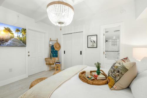 a white bedroom with a bed with a chandelier at Carpe Diem - Seas The Day in Key Colony Beach