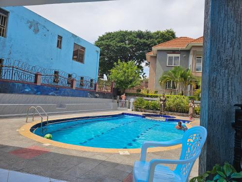 a swimming pool with a chair and a house at HILLS APARTMENTS in Kampala