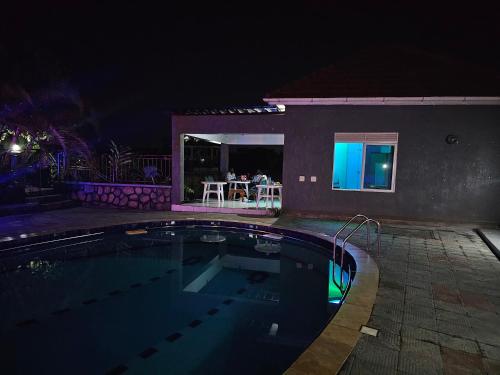 a swimming pool in front of a house at night at HILLS APARTMENTS in Kampala