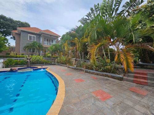 a swimming pool in front of a house with palm trees at HILLS APARTMENTS in Kampala