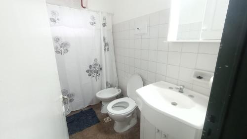 een witte badkamer met een toilet en een wastafel bij COMPLEJO MAINUMBI CENTRO in Mercedes