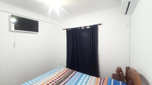 1 dormitorio con 1 cama con cortina negra en COMPLEJO MAINUMBI CENTRO en Mercedes