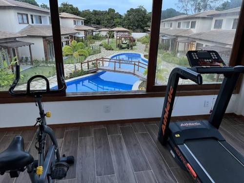 a gym with a treadmill and a view of a pool at Village 115 Barra Grande (Viva Barra) in Marau