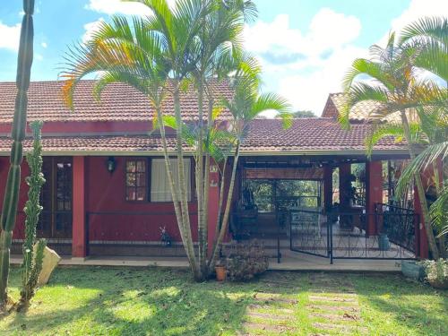 een rood huis met palmbomen ervoor bij Villa Pietá in Brumadinho