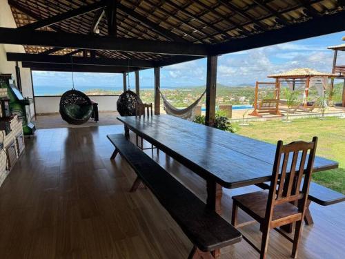 a wooden table and chairs in a room with a view at 6 Suites, banheira, Piscina, no coração da Região dos Lagos in São Pedro da Aldeia