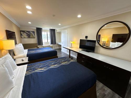 Habitación de hotel con 2 camas y espejo en Vista Inn, en Vista