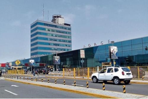 a white car driving down a road in front of a building at Modern Apartment close to the airport in Lima