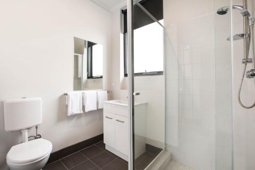 a bathroom with a toilet and a glass shower at Nightcap at St Albans Hotel in St Albans