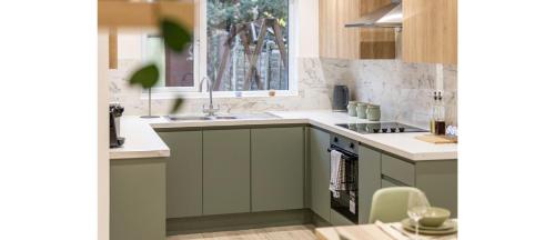 uma cozinha com armários verdes e um lavatório em Essex Vibes: Modern, Funky, & Spacious 4-Bed House em Southend-on-Sea
