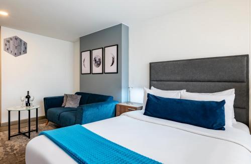 um quarto com uma cama grande e um sofá azul em Torre Acqua Lofts - Downtown Bogota em Bogotá