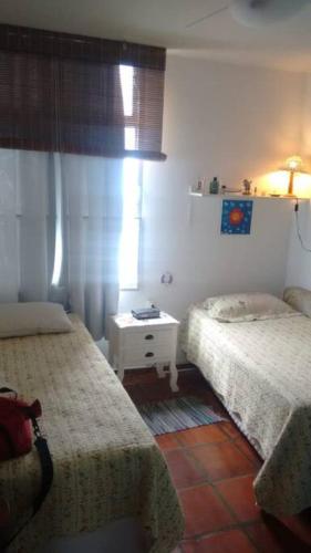 a bedroom with two beds and a table in it at Apto charme frente para a praia in Itanhaém