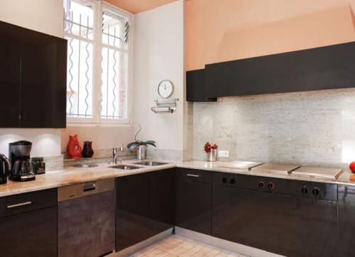 a kitchen with black cabinets and a sink and a window at Villa Persienne in Cannes