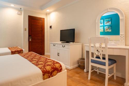 a bedroom with a bed and a desk with a television at Le Soleil de Boracay Hotel in Boracay