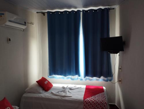 São João GrandeにあるPousada Flóridaの青いカーテンと窓付きのベッドが備わる客室です。