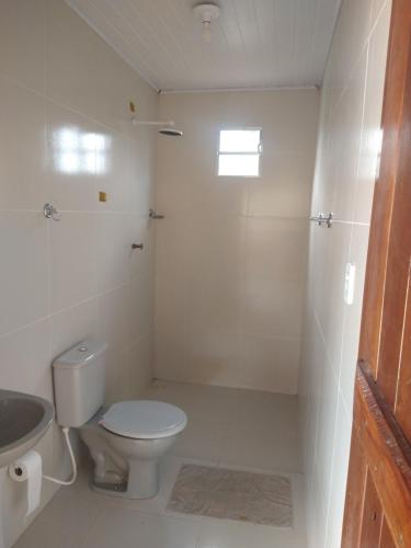 a white bathroom with a toilet and a sink at Chalé Santa Rita in Bonito