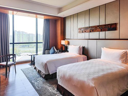 a hotel room with two beds and a window at HUALUXE Yangjiang City Center in Yangjiang