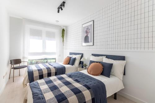 een slaapkamer met twee bedden met blauw en wit bij AkomodaT en nuevo y precioso en Algorta con parking in Getxo