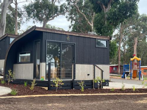 a black and gray tiny house with a playground at Phillip Island Park Lane Holiday Park in Cowes