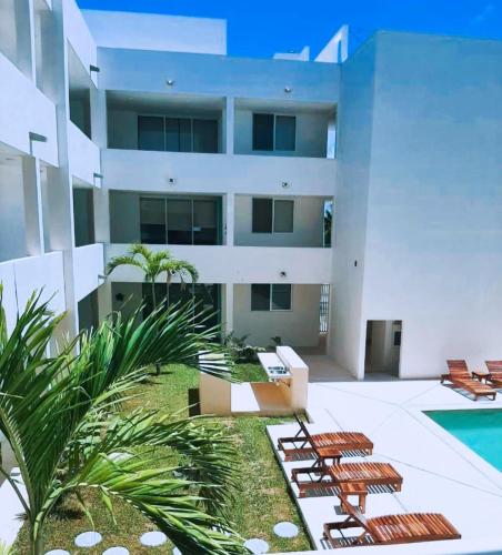 a building with lounge chairs and a swimming pool at Chicxulub Puerto Beach Penthouse in Chicxulub