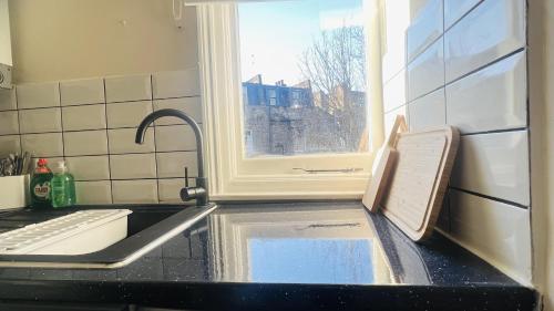 a kitchen sink with a window and water in it at Impeccable 1 Bedroom Flat in Central London in London