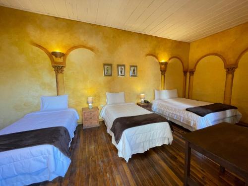 2 Betten in einem Zimmer mit gelben Wänden in der Unterkunft NASS Casa del Aguila in Cuenca