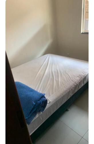Una cama con sábanas blancas y una toalla azul. en TALLYS, en Belo Horizonte