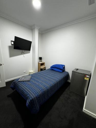 a bedroom with a bed with a blue blanket at GHK - Grand Hotel Kalgoorlie in Kalgoorlie