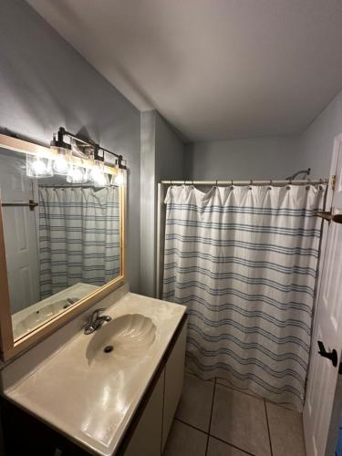 y baño con lavabo y ducha con espejo. en Ocean City, MD Waterfront Villa en Ocean City