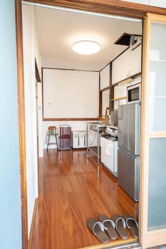 a room with a kitchen with a table and a refrigerator at かぐら庵 in Kitakata