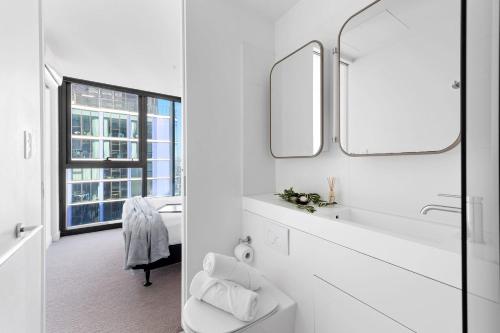 a white bathroom with a sink and a mirror at A Cozy & Comfy 2BR Apt Up in the Clouds Near CBD in Melbourne