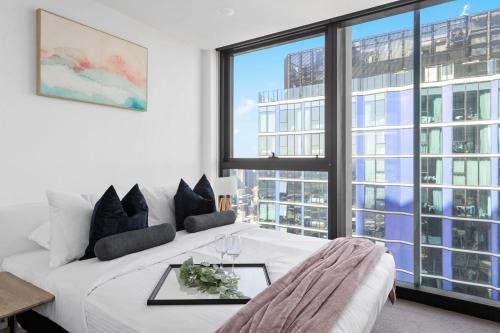 uma sala de estar com uma cama branca e janelas grandes em A Cozy & Comfy 2BR Apt Up in the Clouds Near CBD em Melbourne