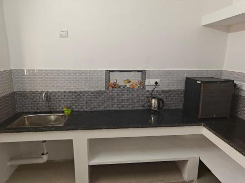 a kitchen counter with a sink and a microwave at Thirunallar Heaven Homes in Tirunallār